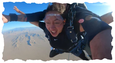 Excited woman tandem skydiving over the desert